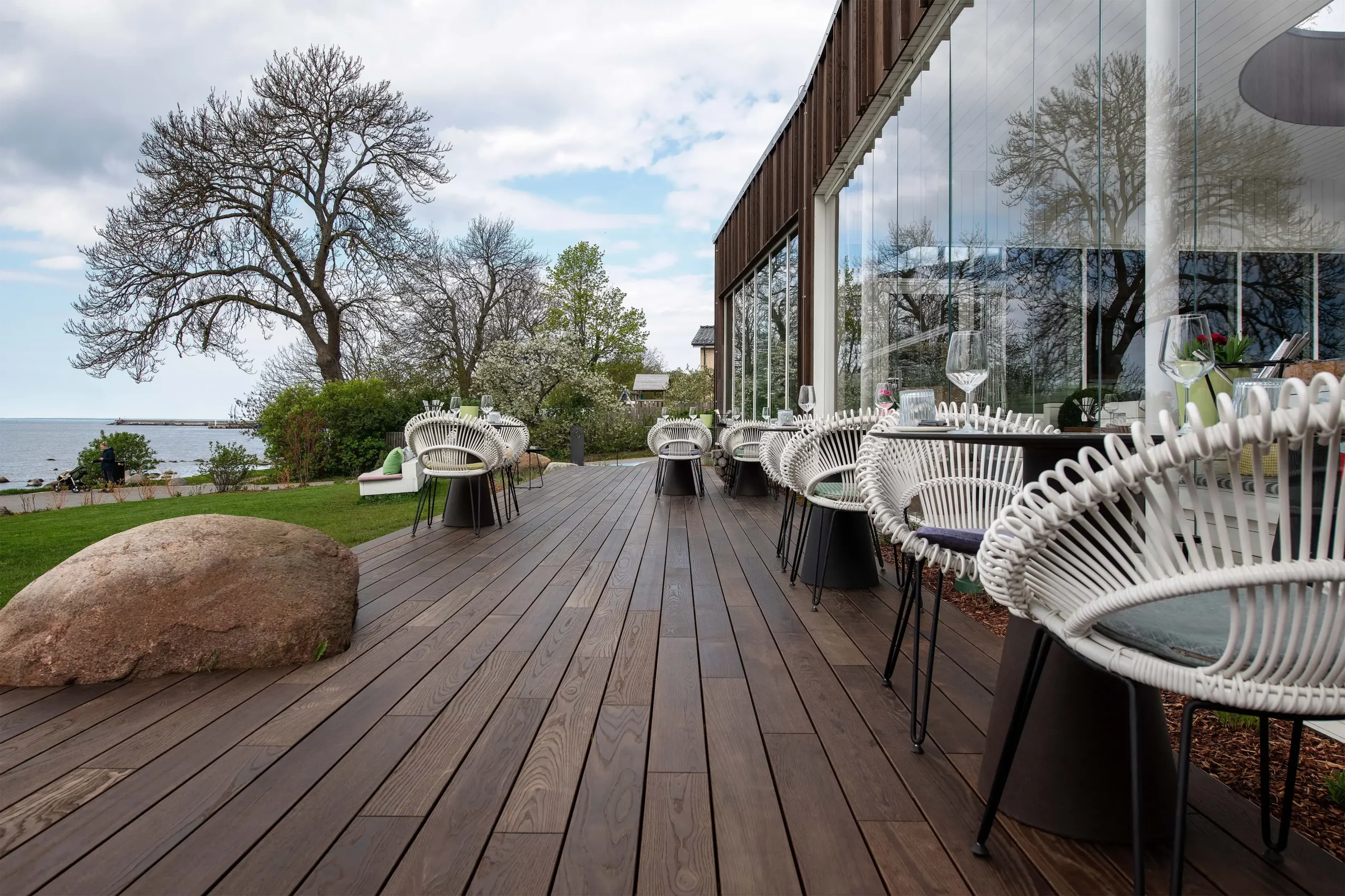 Restaurantterrasse mit Thermoesche-Dielen am Wasser. Terrasse de resto en frêne thermo au bord de l’eau.